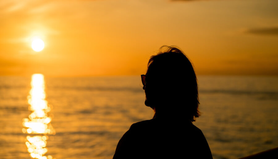 Image of a woman looking at a sunset over the sea